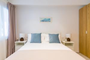 ein Schlafzimmer mit einem großen weißen Bett mit blauen Kissen in der Unterkunft Starhost - Mazzini Apartments in Salerno