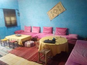 ein Zimmer mit 2 Tischen und einem Sofa mit rosa Bettwäsche in der Unterkunft Moha House in Merzouga