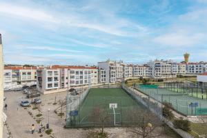 einen Tennisplatz mitten in einer Stadt mit Gebäuden in der Unterkunft Sunny 2 BDR Apartment by LovelyStay in Charneca
