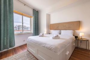 - une chambre avec un lit et une grande fenêtre dans l'établissement Sunny 2 BDR Apartment by LovelyStay, à Charneca