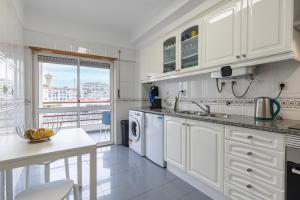 cocina blanca con fregadero y lavavajillas en Sunny 2 BDR Apartment by LovelyStay en Charneca