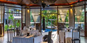 a restaurant with white tables and chairs and windows at Villa Samadhi by Samadhi - Adults Only in Kuala Lumpur