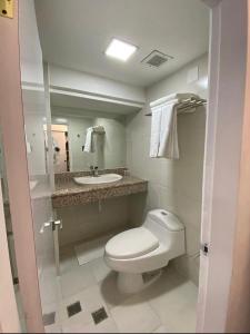 a bathroom with a white toilet and a sink at HOTEL PRINCESA PLAZA in Maracay