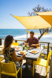 un hombre y una mujer sentados en una mesa comiendo en la playa en Casa de Mar Hotel And Villas, en El Sunzal
