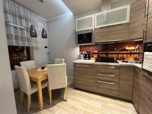 a kitchen with a wooden table and white chairs at Copernicus Dream Apartment Toruń Stare Miasto in Toruń