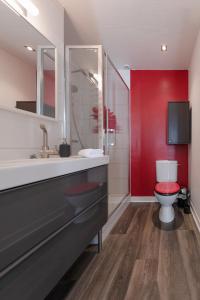 ein Bad mit einem WC und einer roten Wand in der Unterkunft KER UHEL - Charmant appartement plein centre in Saint-Renan