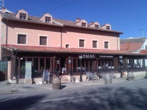 a large pink building with tables and chairs on a street at Hostal restaurante Villa de Sepúlveda in Sepúlveda