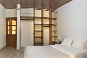 1 dormitorio con cama blanca y estante para libros en Céntrico-A pie del mar y del Casco histórico+A/C, en Santa Marta