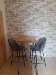 a wooden table and two chairs in front of a brick wall at הבית בואדי 