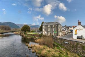 a river in a small town next to a building at Glan Conwy House One and Two Bedroom Apartments in Llanrwst