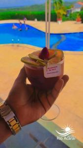 una persona sosteniendo una taza de comida frente a una piscina en Hotel Rio Acaraí, en Camamu