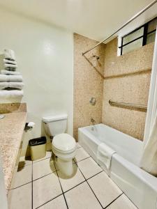 a bathroom with a toilet and a bath tub at Rodeway Inn in Santa Ana
