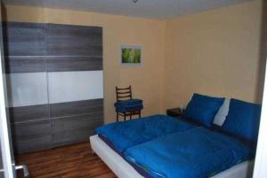 a bedroom with a blue bed and a chair at Ferienhaus Kaffenberger in Michelstadt