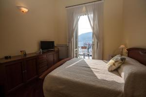 a bedroom with a bed and a television and a window at Tremezzo Bella Vista - lake front - lake view in Tremezzo