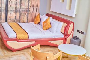 a bed in a room with a table and chairs at Wilsen Hotel Nansana in Kampala