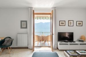 a living room with a television and a balcony at Vista Azzurra in Sala Comacina