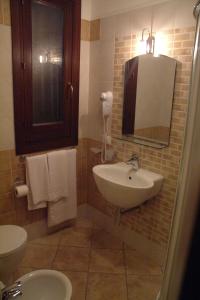 a bathroom with a sink and a toilet and a mirror at Hotel Sikania in San Vito lo Capo