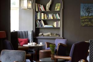 um quarto com uma mesa e cadeiras e uma prateleira com livros em The Close Hotel em Tetbury