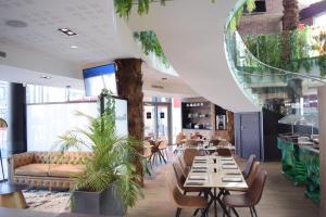 a restaurant with wooden tables and chairs and plants at SoBlue Hôtel in Antibes