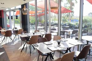 a restaurant with tables and chairs and windows at SoBlue Hôtel in Antibes