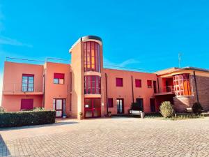 un gran edificio rosa con ventanas rojas en una calle en Regina Del Mare Holiday Apartments en Tirrenia