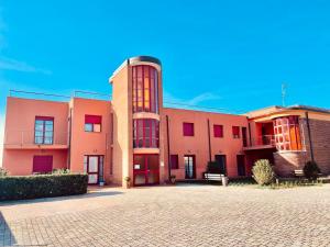 a large pink building with red windows on a street at Regina Del Mare Holiday Apartments in Tirrenia