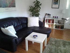 a living room with a black couch and a white coffee table at Ferienwohnung am Wald in Erbach im Odenwald