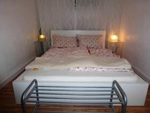 Una cama blanca con dos luces encima. en Ferienwohnung am Wald, en Erbach