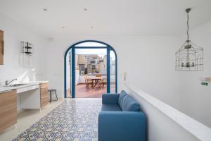 a living room with a blue couch and a kitchen at Chic, Stylish Traditional Townhouse with Terrace - St. Paul’s Bay in St Paul's Bay