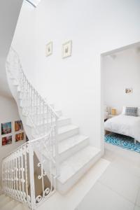 a white staircase in a white room with a bed at Chic, Stylish Traditional Townhouse with Terrace - St. Paul’s Bay in St Paul's Bay