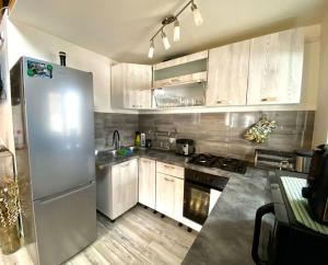 a kitchen with white cabinets and a white refrigerator at Căsuța din CRAI in Zărneşti