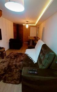 a living room with a couch with a blanket on it at Chalé esquina da CATEDRAL de Canela in Canela +4 photos