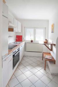 a kitchen with white appliances and a tiled floor at Ferienwohnung Waldblick in Bad König