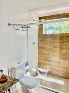 uma casa de banho com um WC e uma cabina de duche em vidro. em Pousada OCEAN em Saquarema