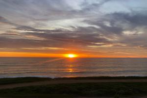 una puesta de sol sobre el océano con la puesta de sol en Casa em frente ao mar c lazer em Barra de São João, en Casimiro de Abreu