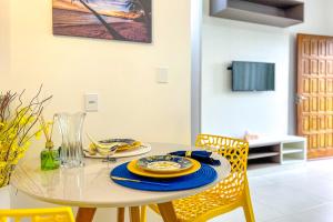 una mesa de comedor con sillas amarillas y una mesa con platos en Casa em frente ao mar c lazer em Barra de São João, en Casimiro de Abreu