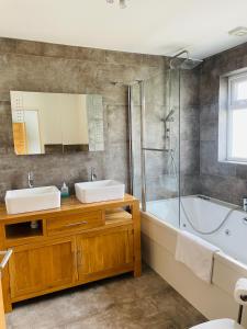 uma casa de banho com 2 lavatórios, uma banheira e um chuveiro em Muller residence em Bristol