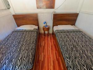 two beds in a small room with wood floors at La Gondola in Montañita