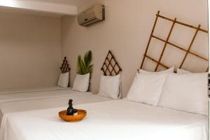 2 Betten mit weißen Kissen und einer Schüssel auf dem Bett in der Unterkunft Pousada Aldeia's in Aragarças