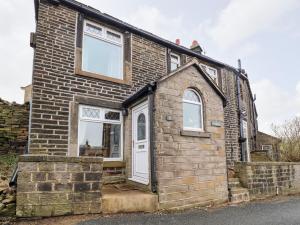 a brick house with a white door and windows at Rivendell in Holmfirth