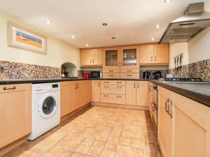 a large kitchen with wooden cabinets and a washer and dryer at Rivendell in Holmfirth