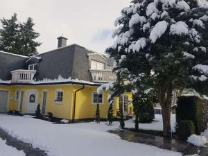 une maison jaune avec de la neige au sol dans l'établissement HAUS Madelaine, à Neu-Anspach