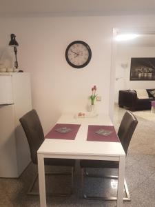 une table blanche avec des chaises et une horloge sur le mur dans l'établissement HAUS Madelaine, à Neu-Anspach