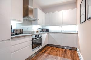 a kitchen with white cabinets and a wooden floor at Be London - The Soho Residences in London