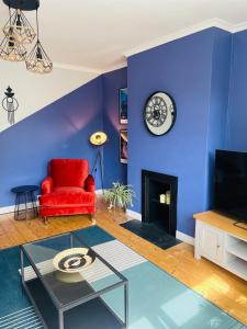 ein blaues Wohnzimmer mit einem roten Stuhl und einer Uhr in der Unterkunft Muller residence in Bristol