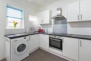 a white kitchen with a washing machine and a sink at Southbeach by Bloom Stays in Hythe