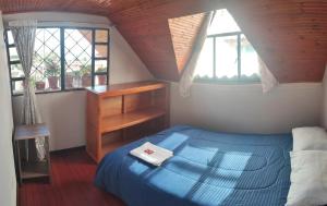 um quarto com uma cama azul e 2 janelas em Alojamiento Chalet - Monguí em Monguí