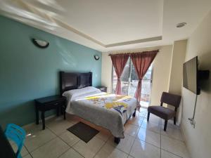 ein Schlafzimmer mit Bett, Schreibtisch und Fenster in der Unterkunft Hotel Santa Fe in Paracho de Verduzco