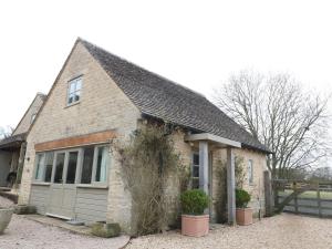 a small brick house with windows and a fence at Pudding Hill Barn Cottage in Cirencester