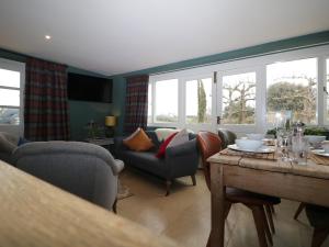a living room with a couch and a table and windows at Pudding Hill Barn Cottage in Cirencester